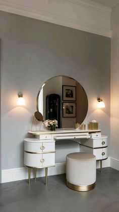 a dressing table with a mirror and stool next to it in a room that has white walls