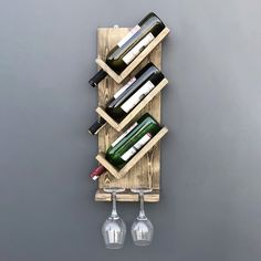 a wine rack with three wine glasses on it and two bottles hanging from the wall