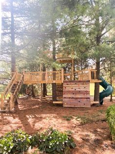 a wooden play set in the middle of a wooded area with stairs leading up to it