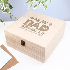 a wooden box with the words new dad and survival kit on it next to a plant