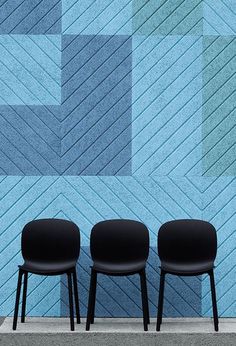 three black chairs sitting in front of a blue wall with geometric designs on it's sides