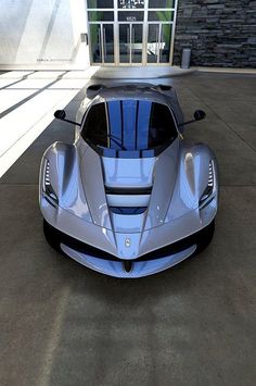 a blue sports car is parked in front of a building with an open door and windows