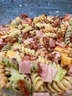 a pasta salad with ham and lettuce in a glass bowl