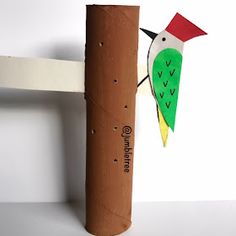 a paper bird is perched on top of a piece of cardboard that's attached to a wooden pole