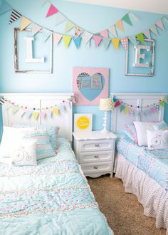 two twin beds in a room with blue walls and white bedding, decorated with colorful bunting