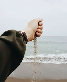 a person holding sand in their hand on the beach