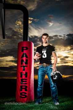 a young man holding a football helmet standing next to a pole