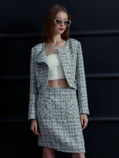 This product is a modern rendition of a classic tweed mini skirt, featuring an asymmetrical cut that lends a contemporary edge to the timeless fabric. The skirt is meticulously tailored to sit comfortably at the waist, cascading into an off-kilter hemline that makes a bold fashion statement. Paired with a coordinating cropped jacket, this ensemble is both polished and trendsetting. - The mini skirt is cut with an asymmetrical hemline, offering a fresh take on traditional tweed.- It is exper Chic Fitted Tweed Jacket, Chic Houndstooth Tweed Dress, Elegant Spring Tweed Jacket With Houndstooth Pattern, Chic Fitted Tweed Skirt, Elegant Tweed Mini Skirt For Winter, Elegant Mini Tweed Dress, Chic Office Tweed Mini Skirt, Chic Tweed Mini Skirt, Elegant Tweed Mini Skirt Dress For Work