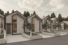 a row of houses sitting next to each other in the middle of a street with trees