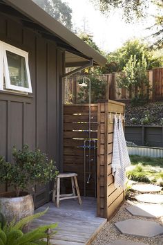 the outside of a house with a shower and wooden steps leading up to it's door