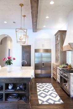 a kitchen with an island, refrigerator and stove top oven in it's center