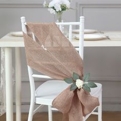 a chair with a bow on it sitting in front of a white table and flowers