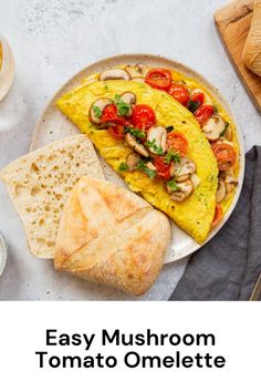 an omelet with mushrooms and tomatoes on it next to some bread, coffee cups and spoons