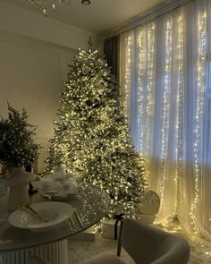 a white christmas tree in a living room next to a window with lights on it