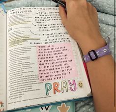 a person holding a pen and reading a book with the word pray written on it