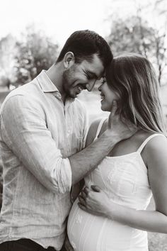 a pregnant couple cuddle together in black and white