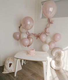 a table with balloons and a cake on it