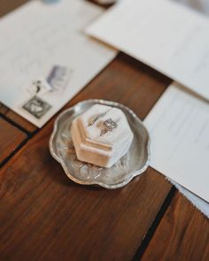 two wedding rings are placed on a napkin in a silver dish next to some envelopes