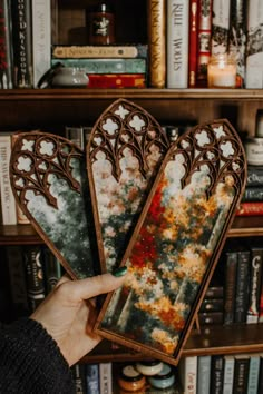 a person holding up some decorative items in front of a book shelf filled with books