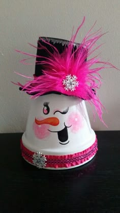 a snowman bell with pink feathers and a black hat on it's head