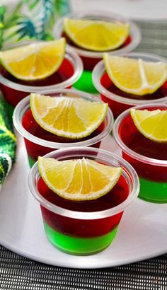 small cups filled with red and yellow jello sitting on top of a white plate