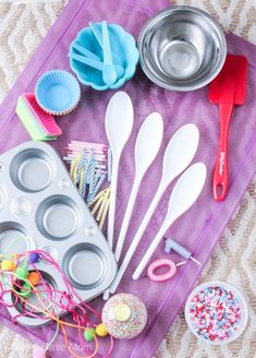 an assortment of baking utensils and cupcake pans on a purple tray