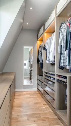 a walk - in closet with lots of clothes on the shelves and drawers next to it