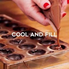 a person is dipping chocolate into small cupcakes on a tray with the words cool and fill