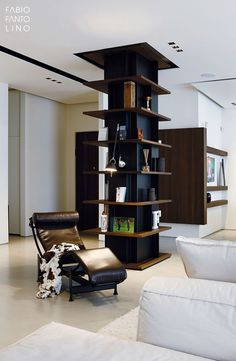 a living room filled with furniture and a tall book shelf next to a white couch