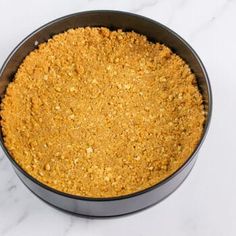 a pan filled with food sitting on top of a white marble countertop covered in crumbs