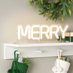 a merry light up sign sitting on top of a shelf next to christmas stockings and stocking