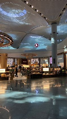 an airport lobby with people walking around and lights hanging from the ceiling over them,