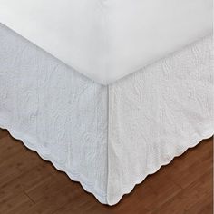 a white bed skirt with ruffled edges on a wooden floor