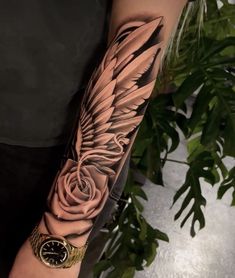 a person with a tattoo on their arm that has a rose and an angel wing