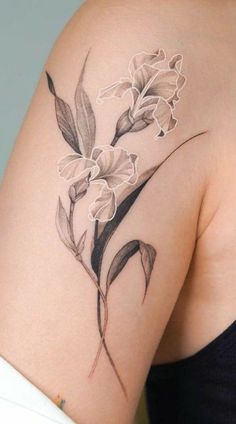 a woman's shoulder with flowers and leaves on the back of her arm,