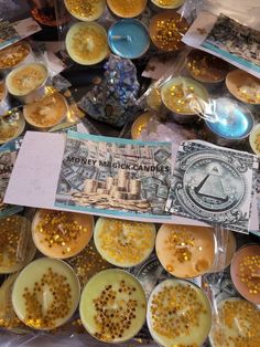 there are many different types of candles on the table with money notes and other items