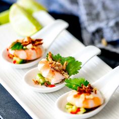 three small white dishes with shrimp and vegetables in them on a tray next to an apple