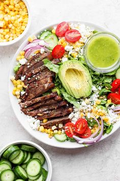 a plate with steak, lettuce, tomatoes, cucumber and avocado on it