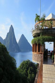 an outdoor dining area overlooking the ocean with mountains in the backgrouds and greenery on either side