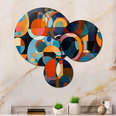 three circular artwork pieces on a wall above a white table with vases and plants