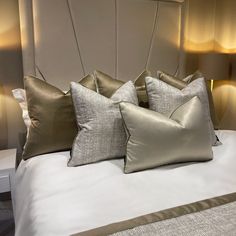 three pillows on top of a bed with two lamps next to it and one is turned off