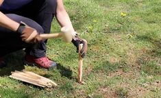 a person holding a wooden mallet in their hand while kneeling down on the grass