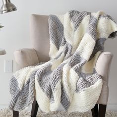 a chair with a blanket on it in front of a white wall and light colored carpet