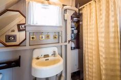 a bathroom with a sink, mirror and shower curtain in it's corner next to a window