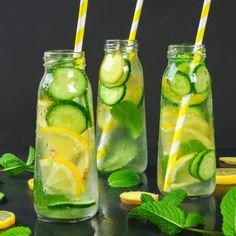 three mason jars filled with cucumber and lemon slices, limes and mint