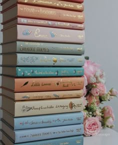 a stack of books sitting on top of a table next to a bouquet of flowers