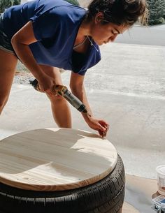 a woman sanding on top of a wooden barrel