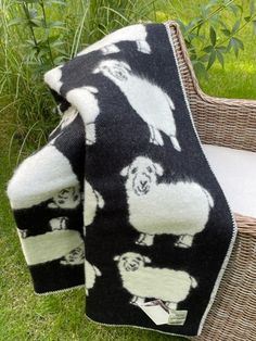 a black and white blanket sitting on top of a wicker chair in the grass