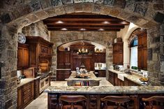 a large kitchen with wooden cabinets and marble counter tops, along with an archway leading to the dining room