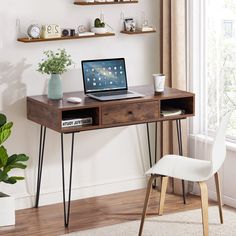 a laptop computer sitting on top of a wooden desk next to a potted plant